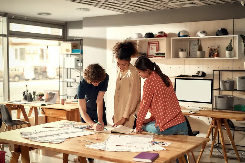 Three entrepreneurs planning their print on demand business and strategies. Brightly lit studio.